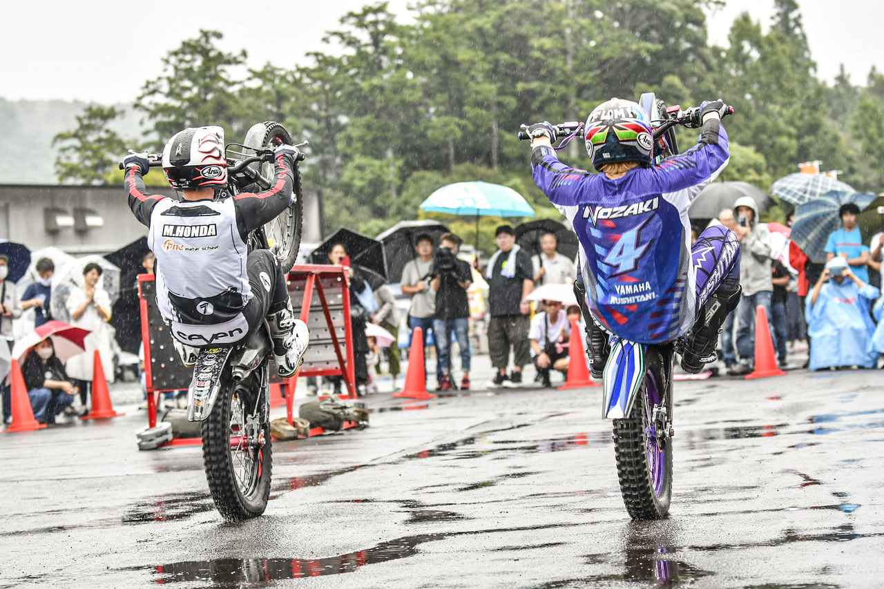 画像: 野崎 史高 選手（右）と、本多 元治 選手（左）によるトライアルデモ。雨が強くなっても、路面がどれだけ濡れてもプロライダーのテクニックは湿らない！