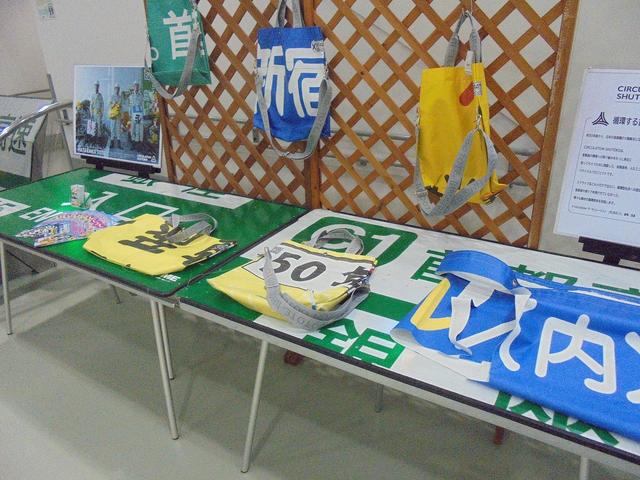 画像: 経路などを示すおなじみの看板や横断幕を材料として再利用して作ったグッズも展示されます。