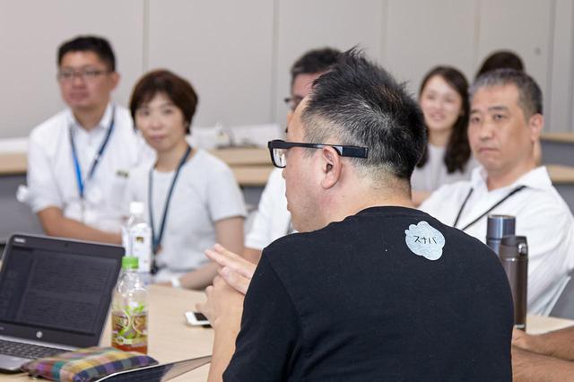 画像: 日立の社員に、アイデアに対するフィードバックをする山田崇氏(手前)。