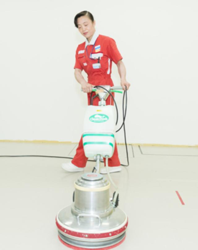 画像: 清掃をしている新津氏 ポリッシャーで床を磨く新津氏。数十キログラムあるポリッシャーを4階まで階段で運ぶこともあるという