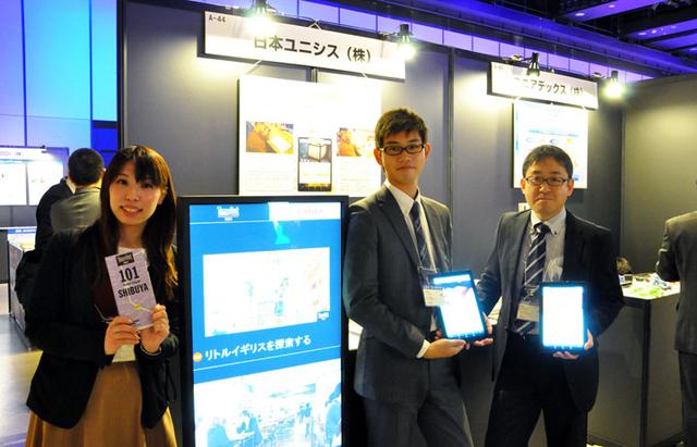 画像: 日本ユニシスのブースでは、タイムアウト東京社とタイアップしたデジタルサイネージを展示。広告映像を一方的に流すだけでなく、お客さまが行きたい飲食店を現在地からの距離や時間、ジャンルなどで絞り込みながら検索ができるインタラクティブな機能を搭載。英語と中国語、韓国語のほか、各地方を多く訪れる外国人観光客の特性にあわせて10か国語以上の言語に対応することもできる。もうひとつ、多言語接客サービス「WaviSaviBavi」も展示。外国人観光客が飲食店に来店した際に、“日本流”のスムーズなコミュニケーションが可能になる。“通”の食べ方を紹介するといった、お客さまの旅心を満足させる良質なコンテンツも搭載している