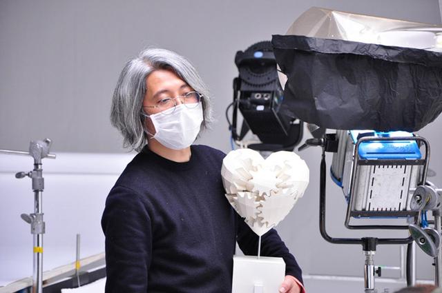 画像: 監督の近藤さん。白いハートは、カミカラ作家の中村さんからお借りしたもの。今回の赤いハートづくりのお手本にした。