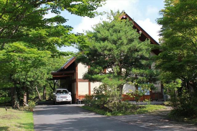 画像: 立派な看板を横目に松に囲まれたアプローチを抜けると現れる三角屋根の木造建築。建物が小さく見える理由は…?