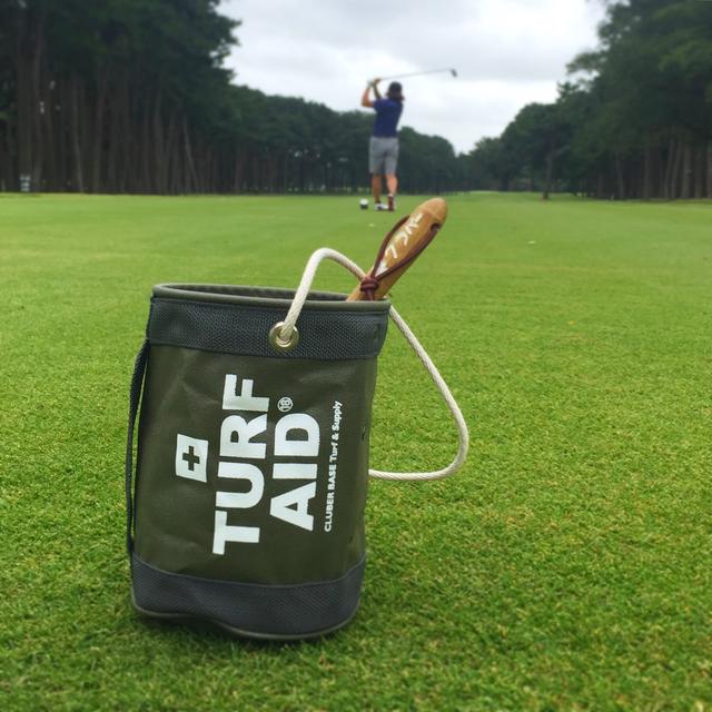 画像: 絆創膏が入った救急箱に「FIRST AID」とあることから目土袋に「TURF AID」と入れたというギアライター高梨祥明さんデザインの目土袋