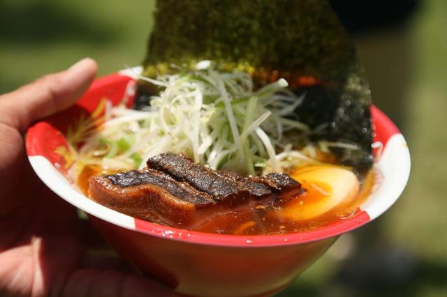 画像: げんこつのように大きなチャーシューにオレンジがかった麺。このオレンジはたまご麺にクチナシを練りこんでいるという