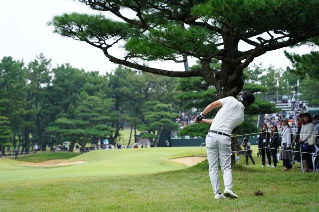 画像: 最終18番パー4で樹の後ろからグリーンを狙う石川遼