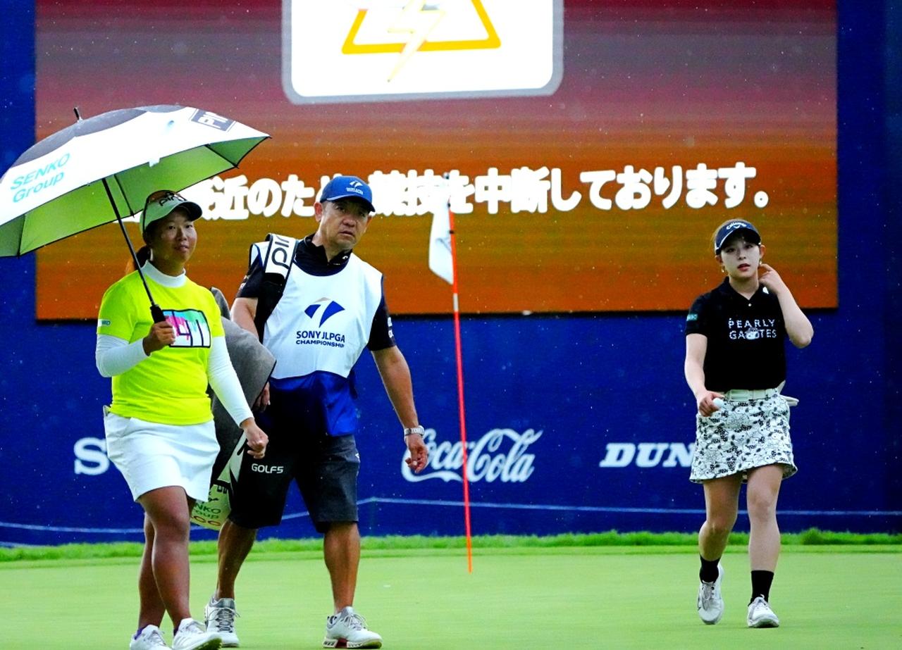 画像: 雷雨接近によりパーパットを残してグリーンを後にする吉田。左は同組の徳永歩（撮影/岡沢裕行）