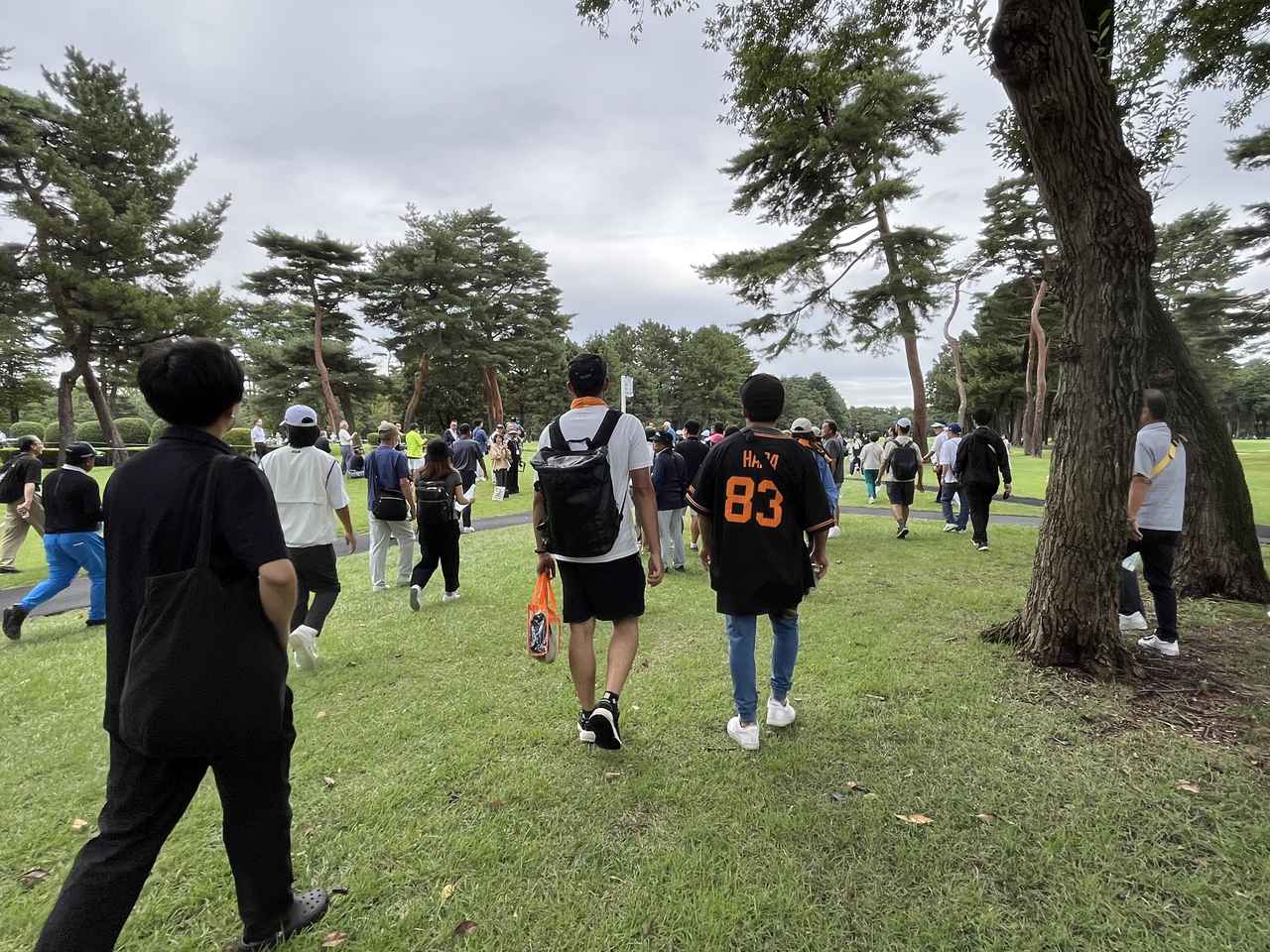 画像: 大ギャラリーを引き連れてのプレー。巨人軍のチームカラー“オレンジ”色のユニフォームなどが目立っていた。「83」の背番号をつけて歩く人も