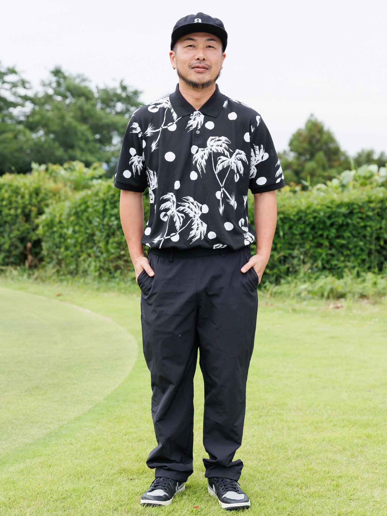 画像: ヤシの木と月をモチーフにしたアロハ柄がオリジナリティを感じさせるポロ。ゆったりシルエットのパンツやキャップ、シューズでストリート感を上手くミックスしています