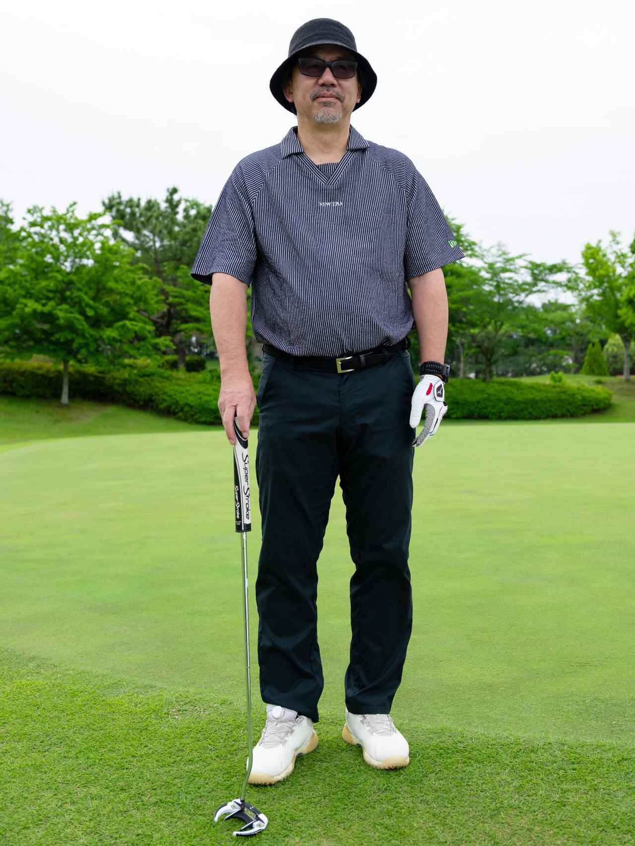 画像: スキッパータイプの襟部分がユニークなストライプ柄シャツ。こなれたバケットハットやゆとりのあるパンツのシルエットを合わせることで大人の遊び心と余裕を感じさせます