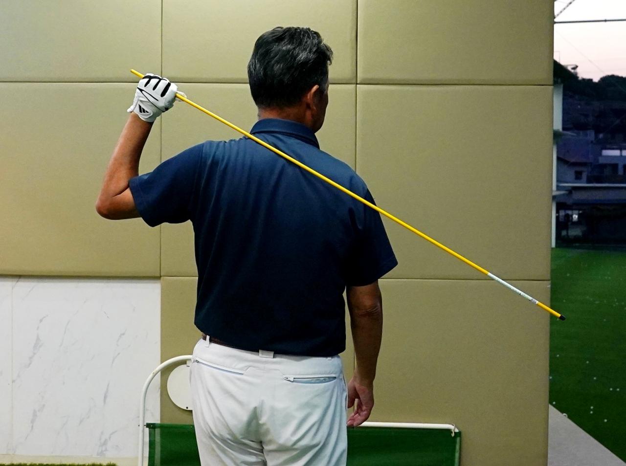 画像: 軽い棒で力を抜いて振る感覚をつかむ。棒が右肩や右肩甲骨に当たるように振ろう