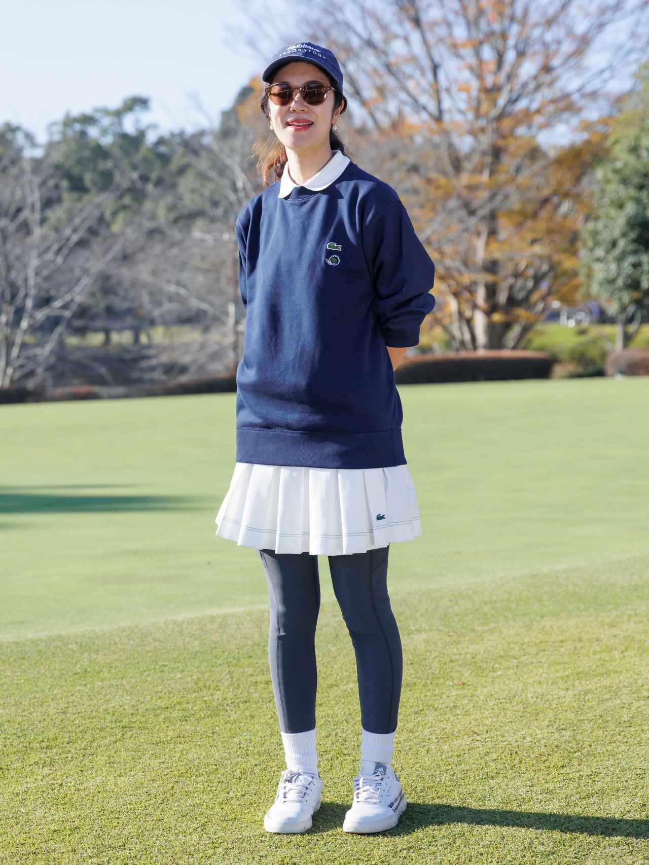 画像: オーバーサイズ気味のネイビーのスウェットシャツに白ポロの襟を出しているのが愛らしいポイント。スカートのボリューム感も適度なバランスで品の良さを醸し出しています