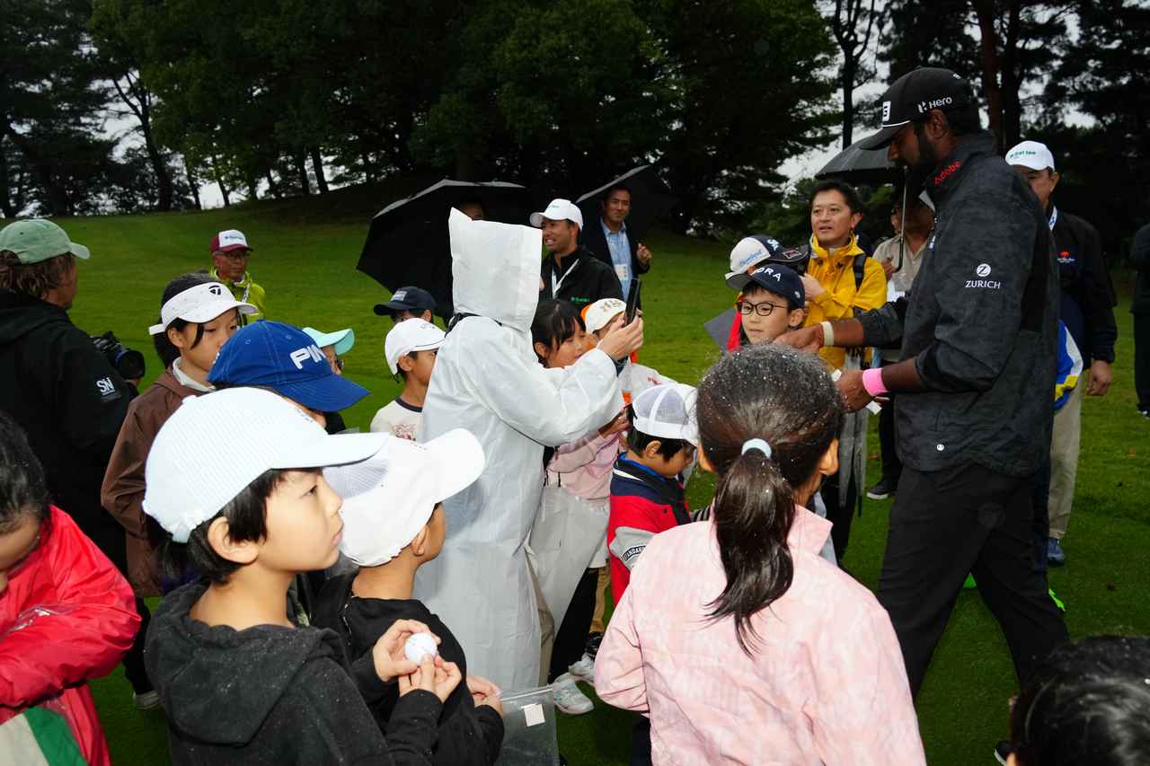 画像: 雨のなか、ホールアウト後のレッスン会終了後、子どもたちに笑顔でサインをするティーガラ（撮影/岡沢裕行）