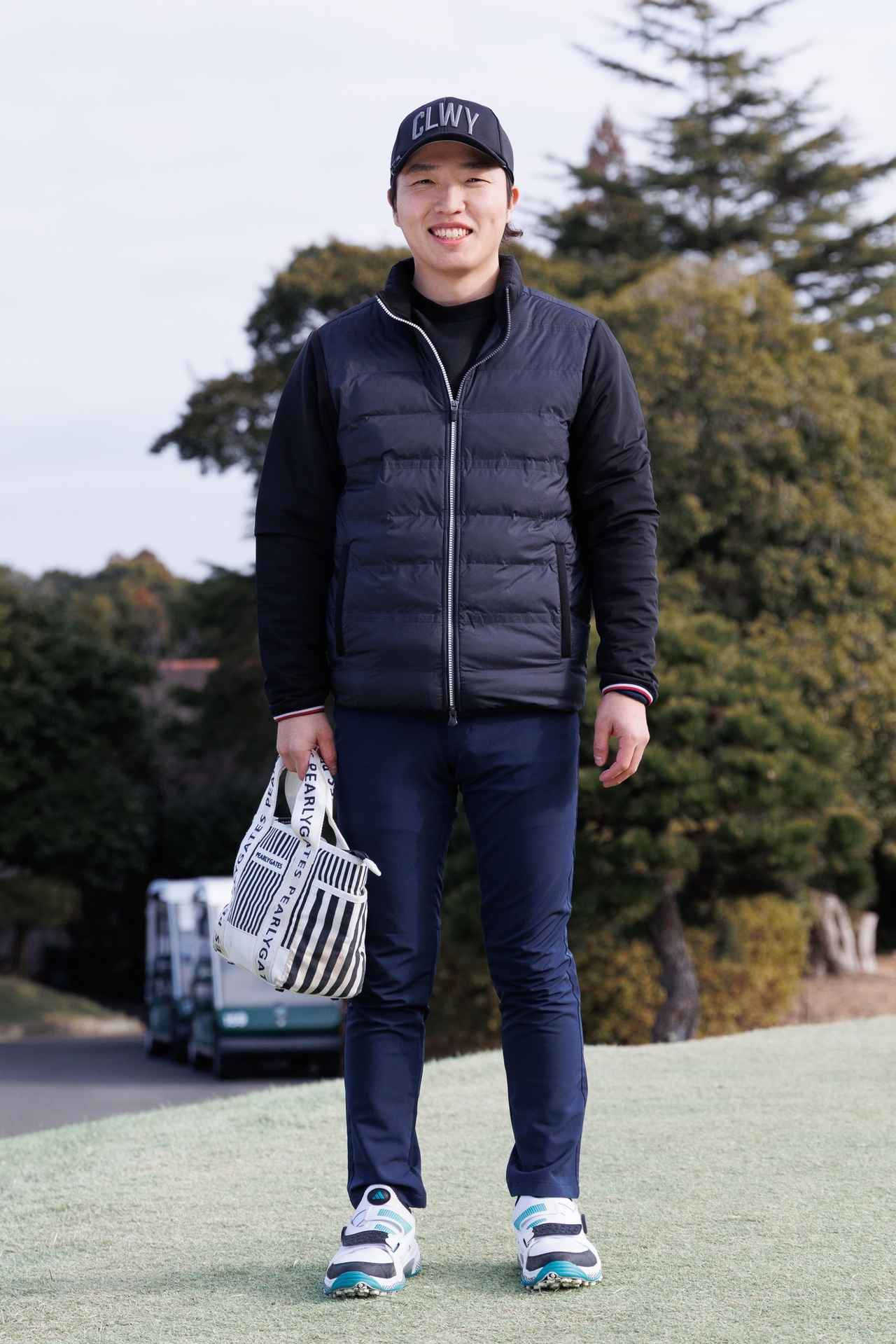 画像: トップスは黒、パンツは紺というコントラストをつけすぎない自然なダークトーン。マリン感のあるカートバッグ、グリーンの効いたシューズも華やかなアクセントとなっています