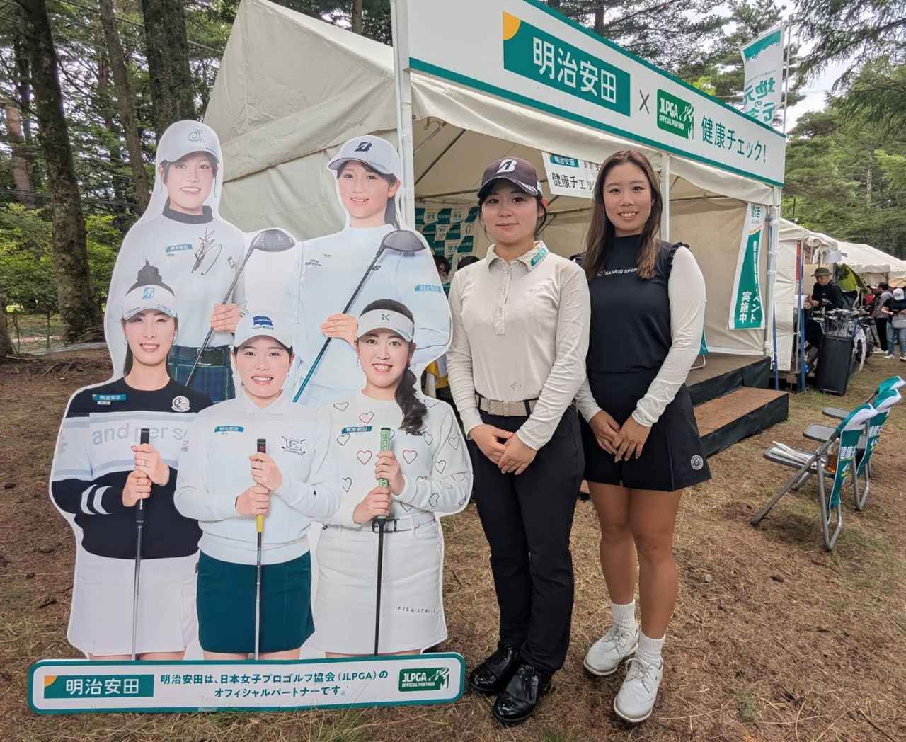 画像: 明治安田生命のブースで健康チェックをした後、所属の人気プロたちの看板と。初めてキャディを務めたという同じ歳で幼馴染の越田泰羽（右）も今年2回目のプロテストを受ける。来年は“所属プロ”を目指す！