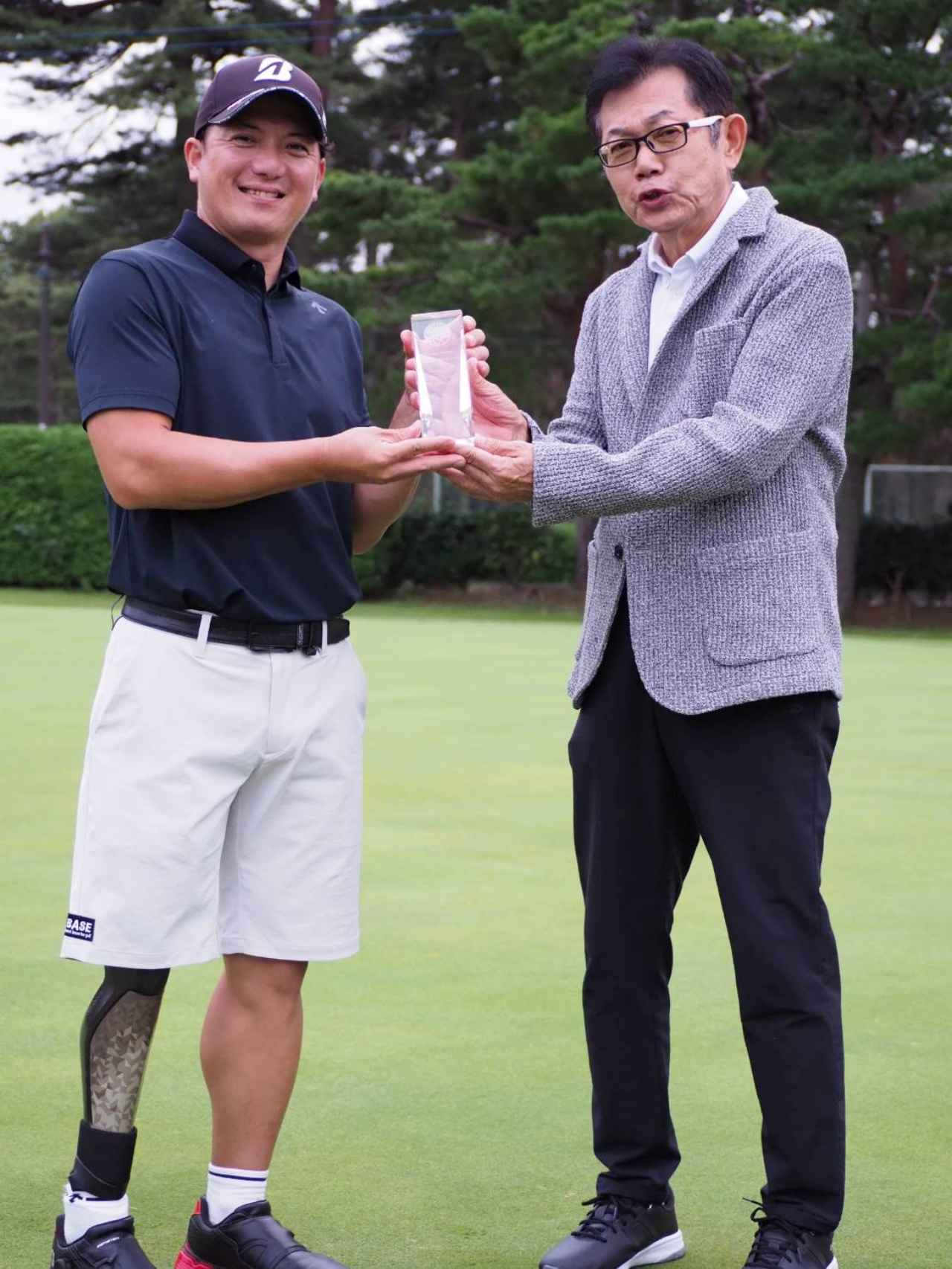 画像: 2連覇の吉田隼人プロを激励する薬師寺広氏。「今回もティーショットが散らばってしまいました。本選は、万全の体調で頑張ります」（吉田）