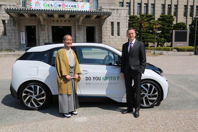 画像: 京都市庁舎前で実施された4月4日の車両引き渡し式では、BMWのクロンシュナーブル社長(右)から門川市長にBMW i3が直接手渡された。
