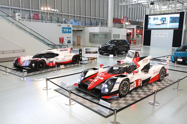 画像: メガウェブの1階に展示された、トヨタ TS050ハイブリッド(手前)とポルシェ 919ハイブリッド。その後ろにプリウスPHVとカイエンが並ぶ。