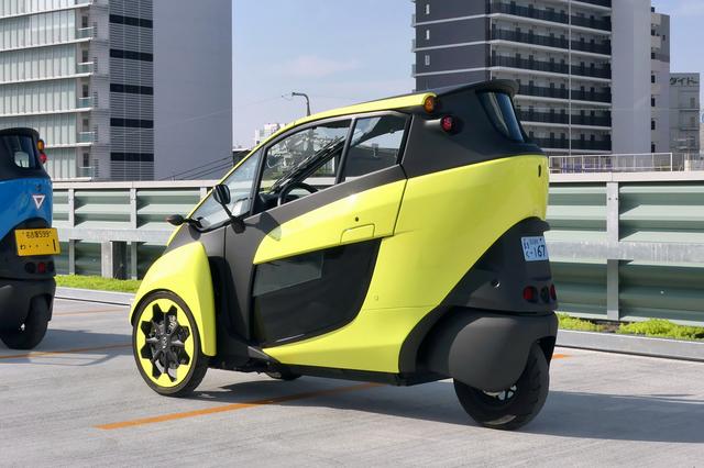 画像: i-ロードは「ミニカー」や「マイクロカー」に分類され、50cc以下の原動機付き3輪車(1人乗り)として青ナンバー登録となる。2人乗りの場合は画像左のように軽自動車の黄色ナンバーとなる。