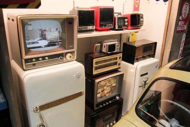 画像: ラジオ、白黒テレビ、冷蔵庫など1960年代当時の電気製品が並ぶ。