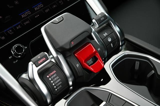 画像: 中央の赤いカバーの下に設けられたスタート/ストップボタン。その上にあるレバーを手前に引くとリバースに入る。左側のレバーでドライブモードを選択する。