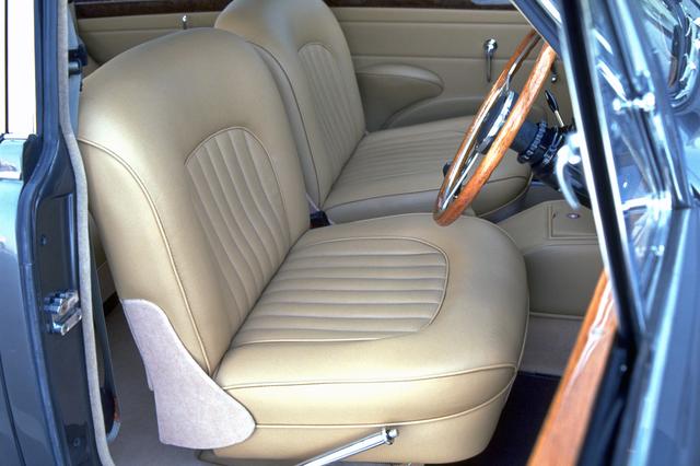 画像: ビスケットと呼ばれる明るいベージュのシートやドアトリムは、コノリーレザー製。運転席右にパーキングブレーキのレバーがある。