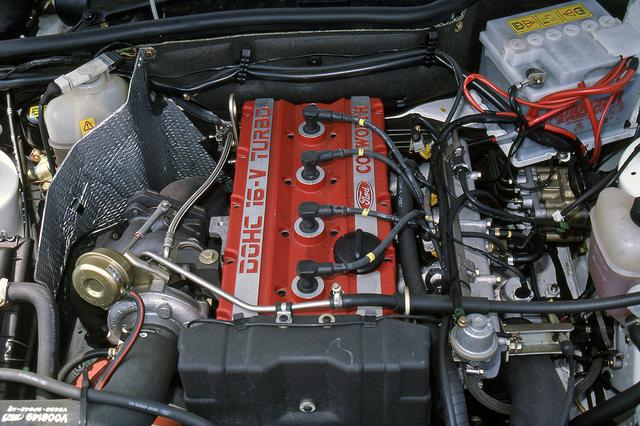 画像: 赤いヘッドカバーには「DOHC 16V TURBO」と「COSWORTH」のロゴが誇らしげに刻まれる。インタークーラーもエンジン前方に備わる。