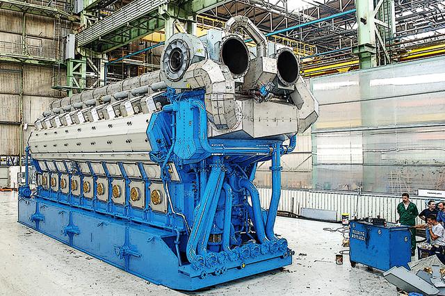画像: コンテナ船の巨大なディーゼルエンジンから見ると小さいが、※ヴァルチラの460mmボアシリーズV型12気筒を4基+V型16気筒を2基も発電機として使う。中速ディーゼルで最適な数だけを駆動するので、燃費と騒音振動・スペースを抑えることができる。 ※ヴァルチラ・ディーゼルは12V(16V)46系だが、掲載画像は最新で一回り大きい18V50DF。
