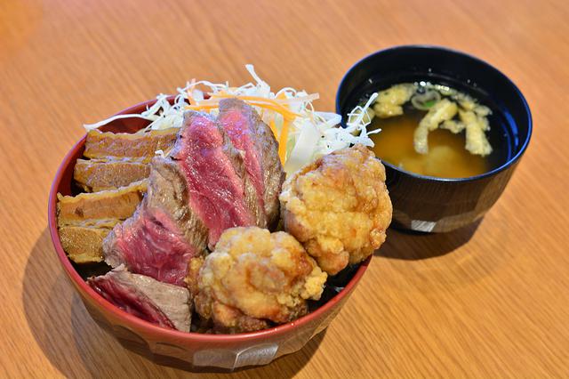 画像: 「肉処 壱丁田」の人気メニュー「肉! よくばり丼」(990円)。ビフテキ、豚の角煮、鶏の唐揚という3種の味が楽しめる。
