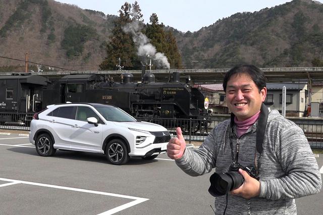 画像: 鬼怒川温泉駅前のパーキングで2台を仲良く並べご機嫌の助川氏。エクリプスクロスPHEVの運転席にはスタッフが待機。(体を伏せてもらってます)