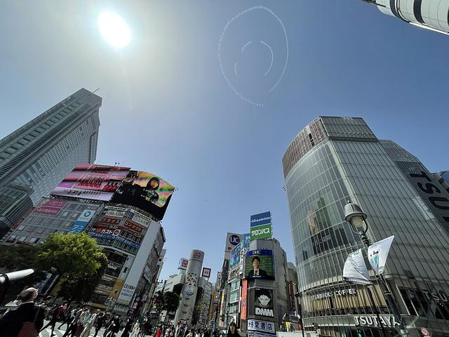画像: 渋谷のスクランブルエッグ交差点上空に描かれたニコちゃんマーク。大勢の人が空を見上げていた。(Pathfinder)