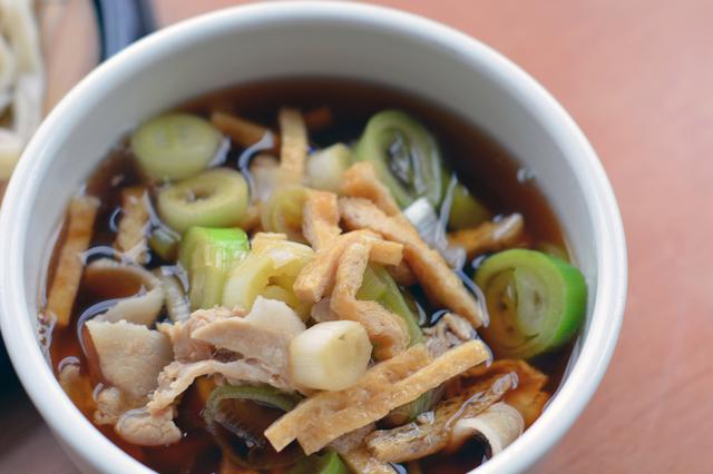 画像: 「肉汁うどん」(830円)のつけ汁。豚肉と太めのネギ、油揚げがたっぷりと入っている。