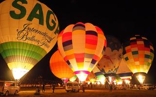 暗闇の中、河川敷一面に広がったバルーンがバーナーの赤い炎に照らされライトアップ。