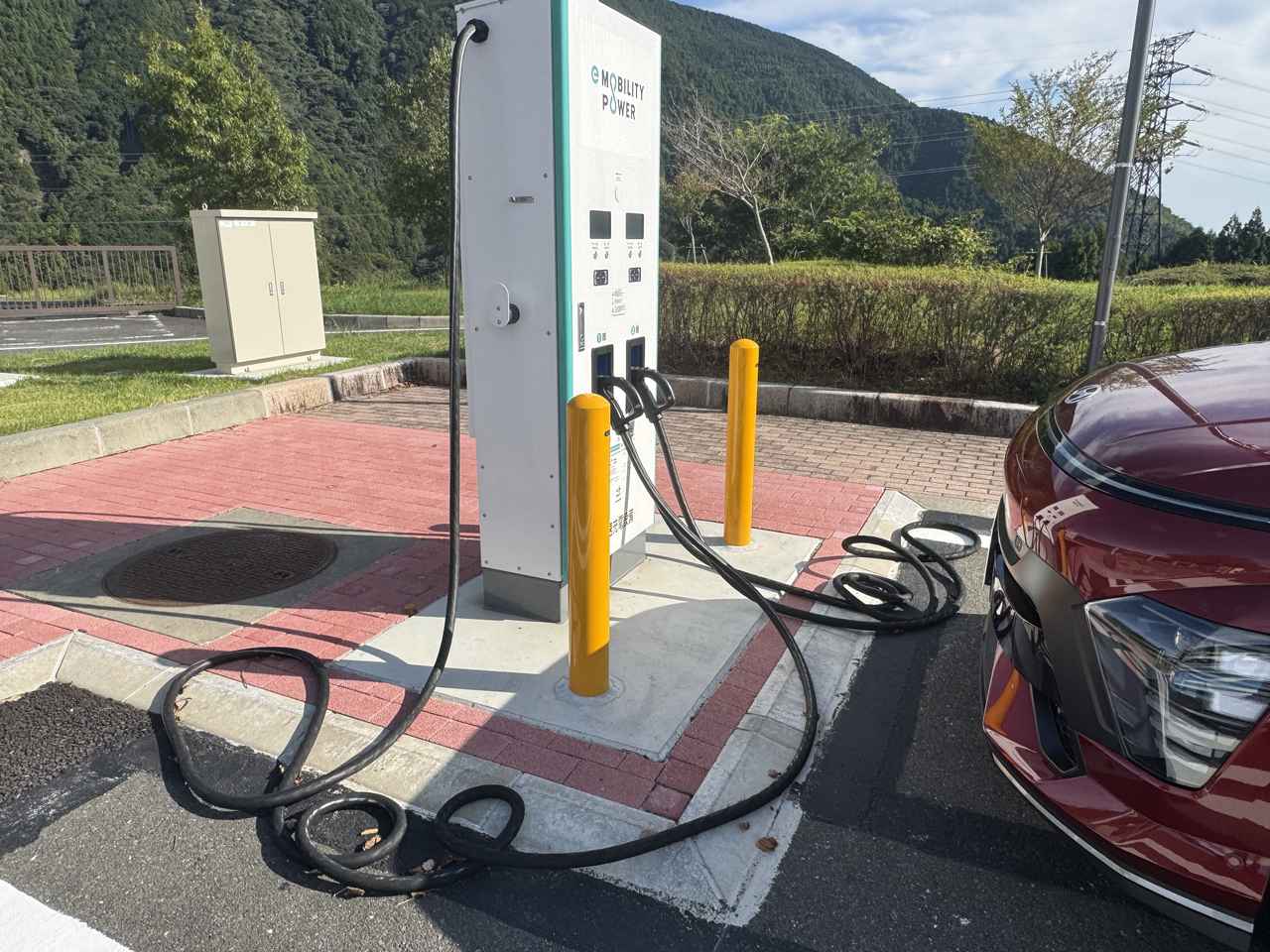 画像: 晴れていればまだいいが、雨が降っていれば、こうして地面に置かれ汚れたり濡れた充電ケーブルを使わなければならないのだ。