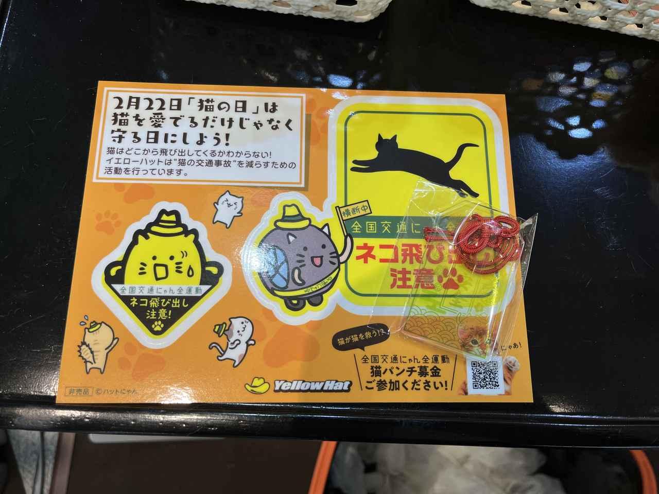 画像: 参加証として配布された非売品のステッカー。ステッカーにはイエローハットのマスコットキャラクター「ハットにゃん」が描かれている。また、目標である「22キロ」の達成者には、画面右にあるアクリル製の「交通安全」お守りがプレゼントされた。