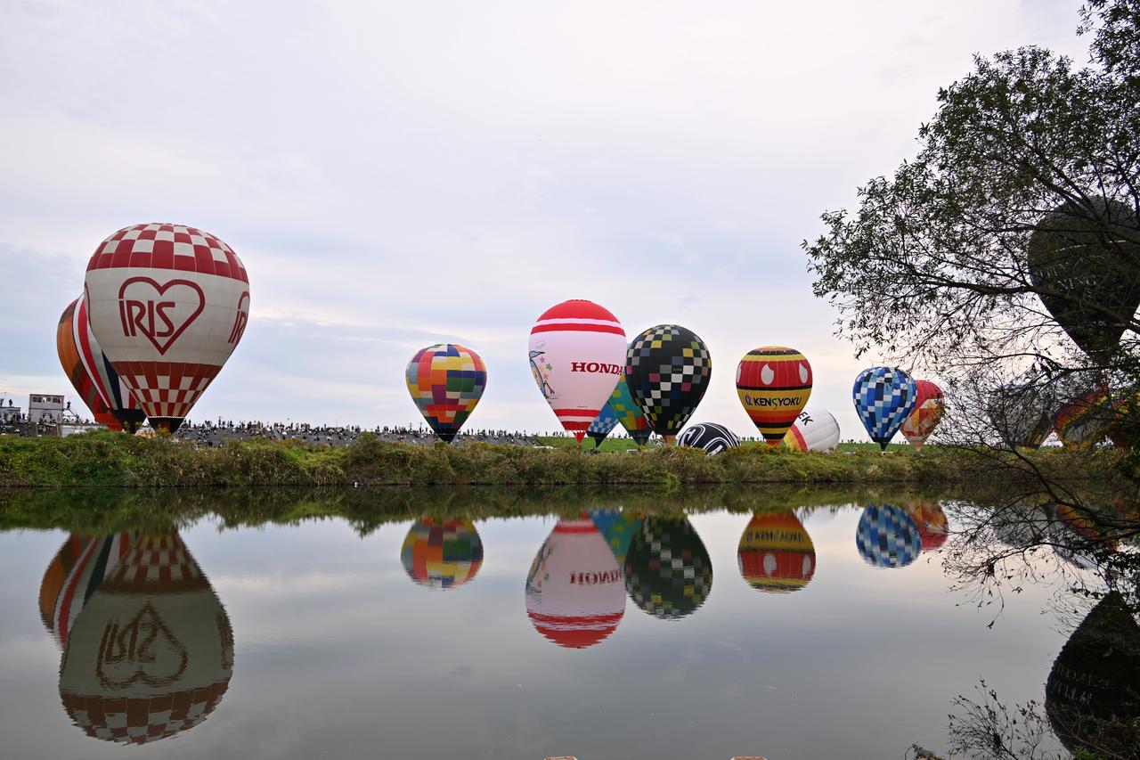 画像: 佐賀インターナショナルバルーンフェスタは、嘉瀬川に反射して映るバルーンも写真映えスポットとして人気である。さらにこれが暗くなってライトアップされると幻想的な雰囲気になる。
