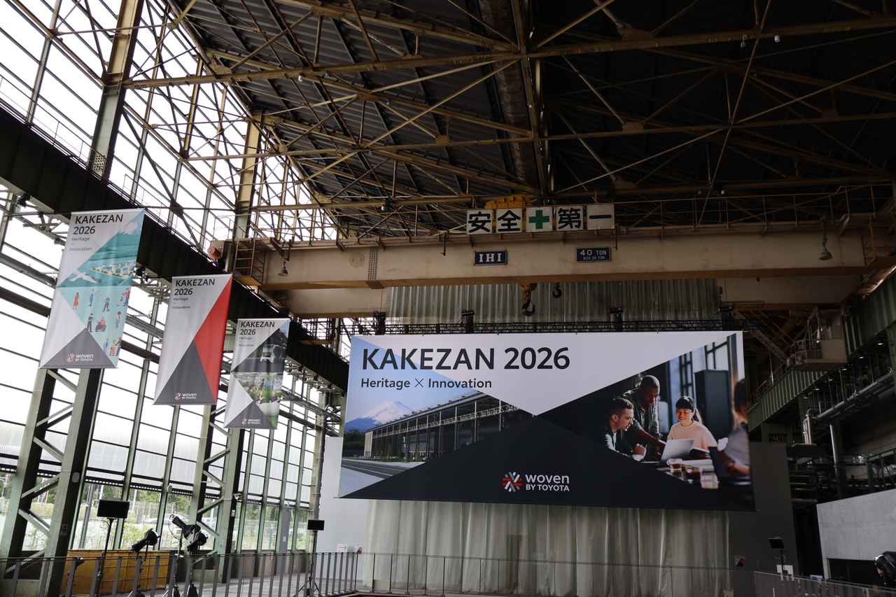 画像: 「KAKEZAN 2026」のイベントが開催されたのは、旧トヨタ自動車東日本 東富士工場跡地のインベンター・ガレージ。垂れ幕の上には大型のクレーンが見られ、工場の面影を見ることができる。