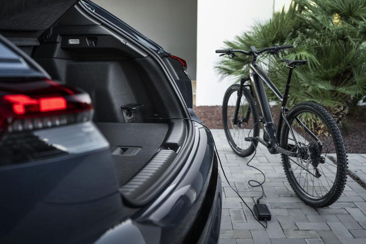 画像: トランク内の家庭用電源ソケット（AC 230V、連続出力2.3kW）で電気機器に直接電力を供給する機能も備わり、例えば電動アシスト自転車の充電が可能。