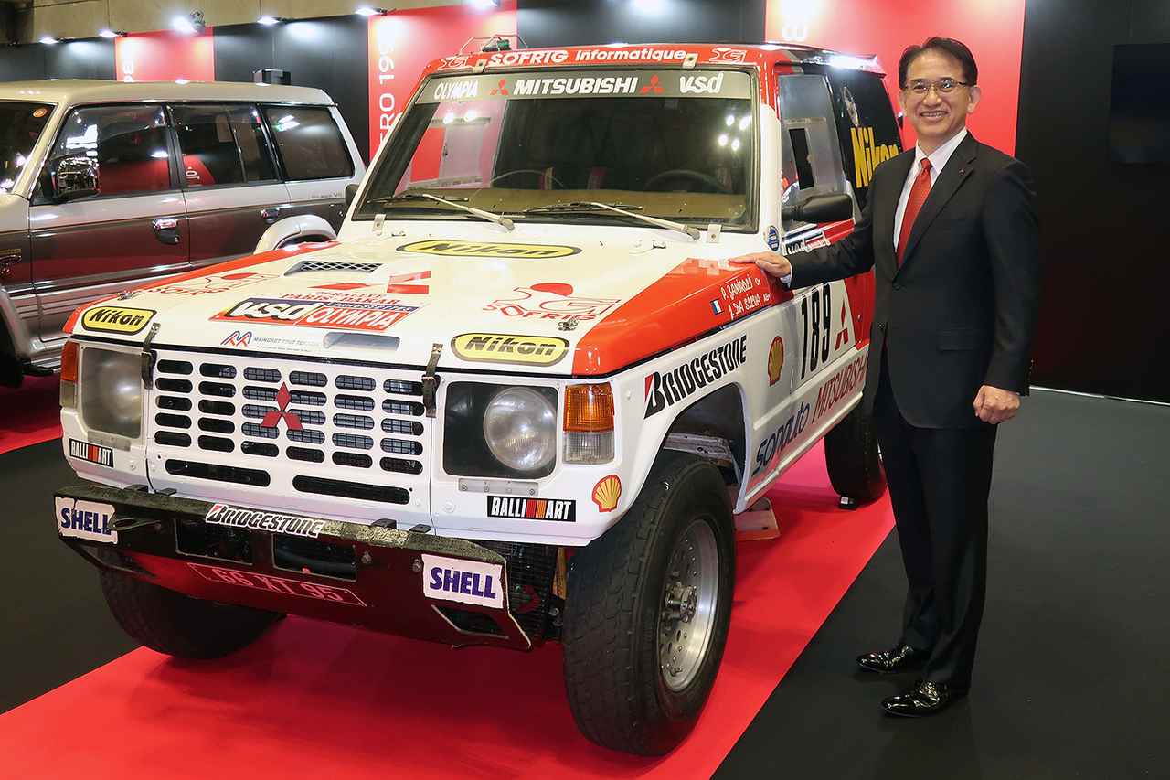 画像: オートモビルカウンシル 2026で、1985年のダカール ラリーで初めて総合優勝した「パジェロ ラリーカー」と岸浦恵介 代表取締役社長 兼 COO。