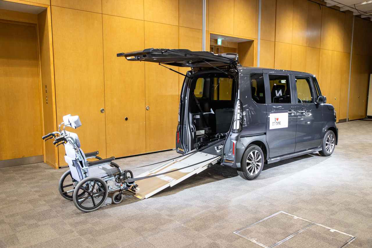 画像: 写真のように3段式のアルミ製スロープを引き出し、車内フロアにある電動ウインチで車いすを引っ張り上げる。車いす仕様車はリアゲート開口部が広く、バンパー下端までリアゲートが開く点が特徴。