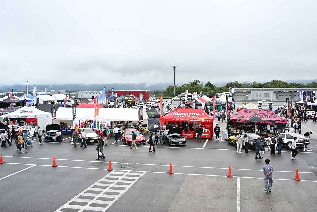 画像: ピット裏に並ぶカスタムパーツメーカーなどの展示ブースの様子。