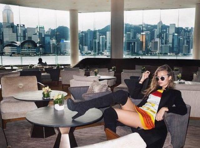 画像: 窓の外のビル街をバックにホテルのロビーでクールにポーズ!
