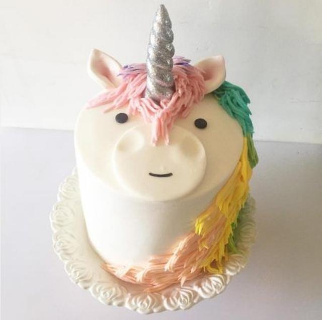 画像: ケーキの側面ではなく上に顔がついたタイプ。シルバーの角に、糸のように絞り出した硬めのクリームで1本1本丁寧に描いたレインボーカラーのグラデーションのたてがみが見事。 Ⓒbaunbon