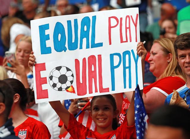 画像: 女子サッカーW杯アメリカ対イングランド戦で「同等のプレー、同等のペイ」というプラカードを掲げるファン。