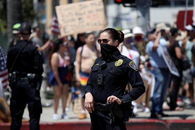 画像: カリフォルニア州サンディエゴで、デモを見守る警察官。(2020年4月26日に撮影)