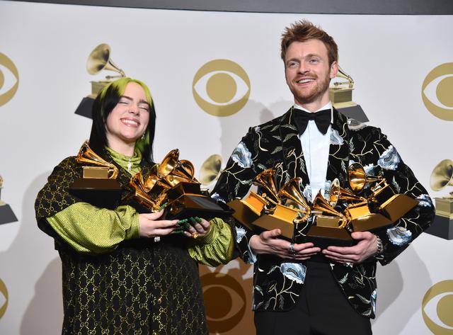 画像: トロフィーを抱えて満足そうな表情を浮かべるビリー・アイリッシュ(左)と兄で音楽プロデューサーのフィニアス・オコネル(右)。