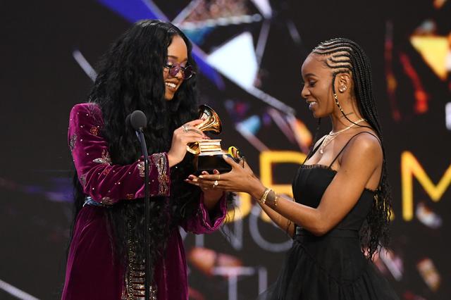 画像: 最優秀楽曲賞のトロフィーを受け取るH.E.R.と、「I Can't Breathe」を共作したティアラ・トーマス。