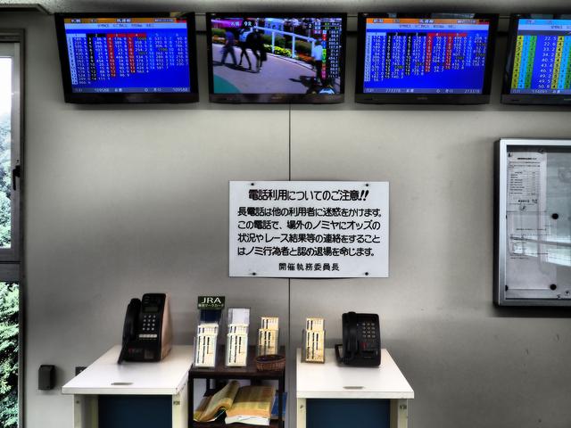 画像: 特観席の端にはなぜか公衆電話が。このご時世において、公衆電話で「ノミ屋にオッズやレース状況を伝える」ヤカラがいるのでしょうか?