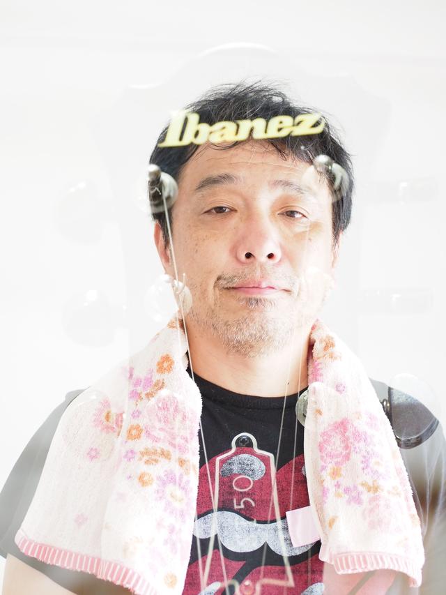 画像: ギターのヘッド+ワタシ。フィーチャリング・俺。どちらもオーバー目の画像を選んだので、なんかよく分かりませんね。昔の「巻き上げ忘れ」フィルムカットみたい。