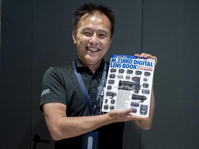 画像: 小城崇史さん。手にしているのは9月28日に発売になったばかりのオリンパスM.ZUIKO DIGITAL LENS BOOK。このムックでは小城さんに執筆いただいています。